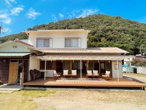 ein Haus mit einer Holzterrasse mit einem Berg im Hintergrund in der Unterkunft 香川県高松市中心部で駐車6台無料の家族向けゲストハウス in Takamatsu
