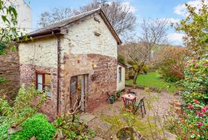 an old stone house with a table in a garden at Garden Cottage Wiveliscombe in Wiveliscombe