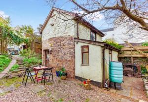 une petite maison en pierre avec une table et des chaises dans l'établissement Garden Cottage, Wiveliscombe, à Wiveliscombe