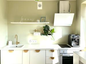 Una cocina con gabinetes blancos y un fregadero. en Green studio Valmiera, en Valmiera