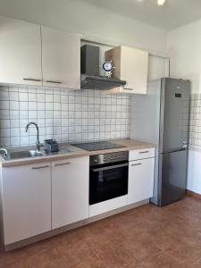 a kitchen with white cabinets and a stainless steel refrigerator at Apartment Noa in Crikvenica