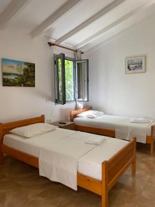 two beds in a room with white walls and windows at Garden Rooms in Himare