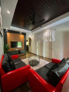 un salon avec un canapé rouge et une télévision dans l'établissement BELLA COTTAGE, à Pantai Cenang