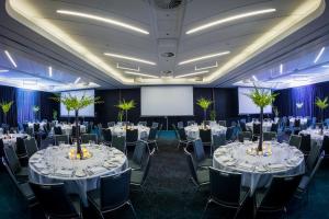a conference room with tables and chairs and a screen at PARKROYAL Darling Harbour, Sydney in Sydney