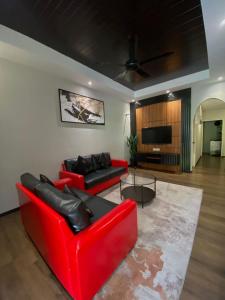 un salon avec un canapé rouge et une télévision dans l'établissement BELLA COTTAGE, à Pantai Cenang