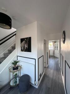 a hallway with white walls and a table and a chair at That's Amore House 3 bedroom house with parking walking distance to Sandbach town in Sandbach