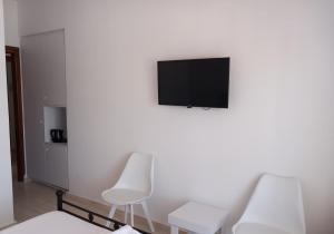 two white chairs and a television on a white wall at Naias in Livadi