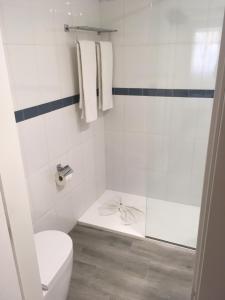 a white bathroom with a toilet and a shower at Comitas Floramar in Cala Galdana