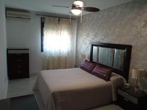 a bedroom with a bed and a ceiling fan at Piso Auringis in Jaén