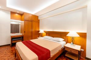 a bedroom with a large bed with a red blanket at Tropicana Suites in Manila