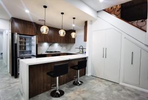a kitchen with white cabinets and black bar stools at Ryde guest house in Sydney