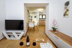 a living room with a television and a table with wine glasses at Nicolas Urban Comfort Living in Souda