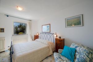 a bedroom with a bed and a chair and a window at Villino Blu in Praiano