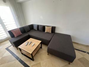 a living room with a black couch and a coffee table at Sousse Beach Appartment FAMILY ONLY in Hammam Sousse