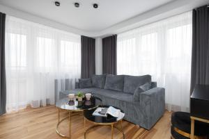 een woonkamer met een grijze bank en een tafel bij Warsaw Center Elegant Studio with City View by Noclegi Renters in Warschau
