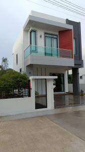 a white house with a red door and a balcony at holiday suratthani in Surat Thani