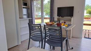 a dining room with a table and chairs and a television at Bungalows Land'shause in Pataias