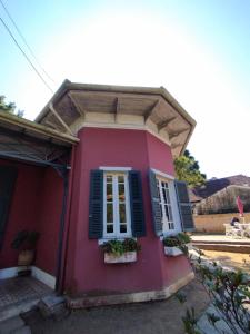 Una casa rosa con contraventanas azules y flores. en Villa Aruanda, en Petrópolis