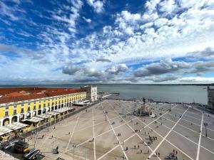 a city square with a cloudy sky and the water at Large apartment on Rua Augusta in Lisbon