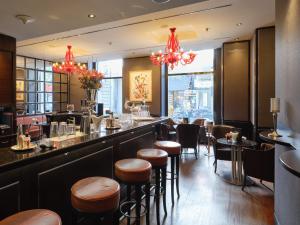 a restaurant with a bar with stools and tables at Hotel Schweizerhof Zürich in Zürich