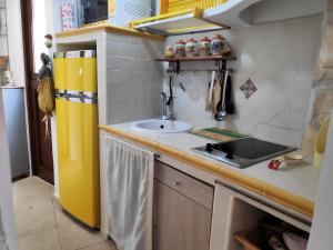 a small kitchen with a sink and a yellow refrigerator at Casa Marilena vista mare in Sperlonga