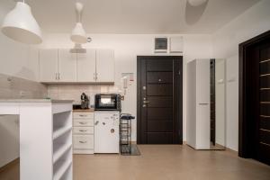 Una cocina con gabinetes blancos y un refrigerador blanco. en La Casa Studio Apartman, en Subotica