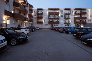 Un estacionamiento con autos estacionados frente a un edificio. en La Casa Studio Apartman, en Subotica