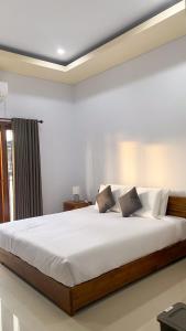 a bedroom with a large bed with white sheets and pillows at Krishna purnama villa sukawati in Saba +4 photos