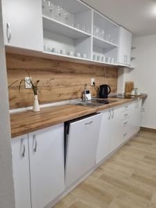 a kitchen with white cabinets and a wooden counter top at Penzión Mateo in Pichne
