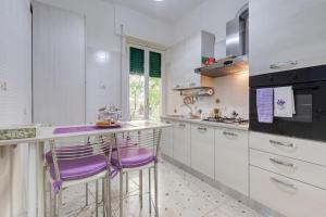 a kitchen with white cabinets and purple stools at Ninuphar Maison - alloggio per uso turistico in Rome