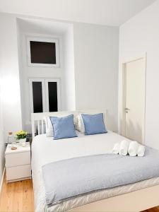 a white bedroom with a large bed with blue pillows at Large apartment on Rua Augusta in Lisbon