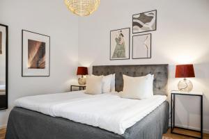1 dormitorio con 1 cama con sábanas blancas y cuadros en la pared en Winstrupsgatan, en Lund