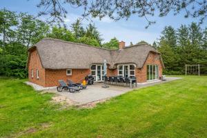 a brick house with a patio and a playground at Beautiful Holiday Home In Husby in Ulfborg