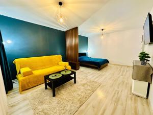 a living room with a yellow couch and a table at BB Apartaments Dream Village in Iaşi