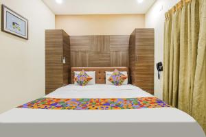 a bedroom with a large bed with a wooden headboard at FabHotel MRV Inn in Chennai