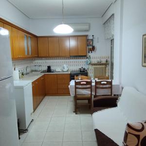 a kitchen with wooden cabinets and a table and chairs at Efchi city center apartment in Katerini