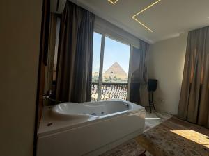 una vasca da bagno bianca in una stanza con finestra di Unique Pyramids View INN a Il Cairo