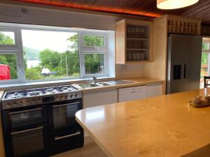 a kitchen with a stove and a sink and a window at Cedarwood Lodge Leenane in Leenaun