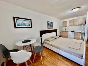 波德戈里察Apartments Jankovic的一间卧室，里面有一张床、一张桌子和几把椅子。