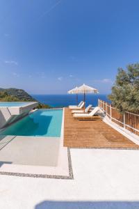 a villa with a swimming pool with chairs and an umbrella at NeRó Villas Lefkada in Tsoukaladhes