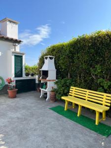 a yellow bench sitting in a yard next to a hedge at Casa das Courelas in Nordeste