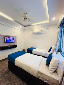 two beds in a hotel room with a tv at VALUE INN in Bangalore