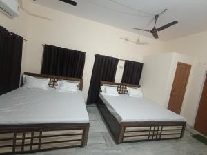 2 letti in una camera con tende nere di RaghuvarDham Delux 2 Double Beds a Ayodhya