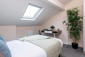 ダービーにあるcheerful double en-suite room with free wifiのベッドと机と窓のある寝室