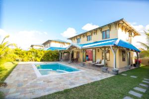 a villa with a swimming pool in front of a house at Orchid Villas Mauritius in Belle Mare