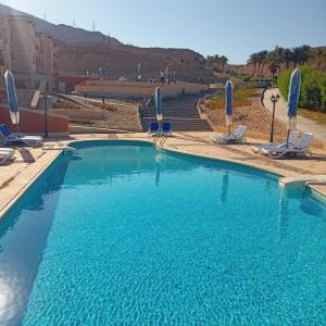 a large blue swimming pool with chairs and umbrellas at Porto Sokhna Heaven Hills Chalet Families ONLY in Ain Sokhna
