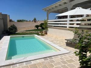 a swimming pool on a patio with an umbrella at MASSERIA FRANTELLA in Grottaglie