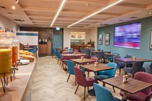 a restaurant with tables and chairs and a large screen at Thistle London Piccadilly in London