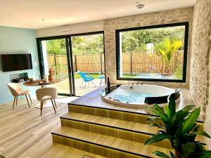 a bathroom with a jacuzzi tub and a living room at Les Suites du Payré - Suite Romance in Saint-Hilaire-de-Talmont