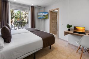 a bedroom with a bed and a desk with a laptop at Vas Málaga Ciudad in Málaga